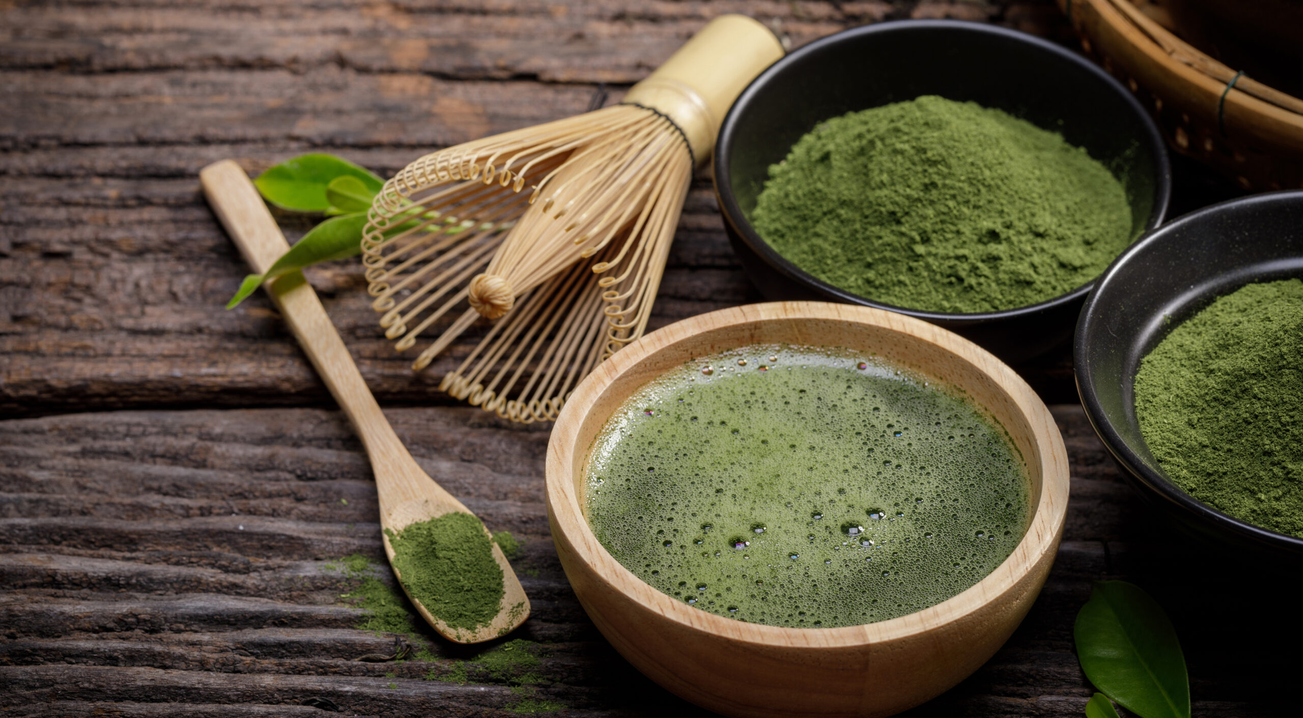 Japanese organic matcha green tea powder in bowl with wire whisk and green tea leaf on wooden background, Organic product from the nature for healthy with traditional style